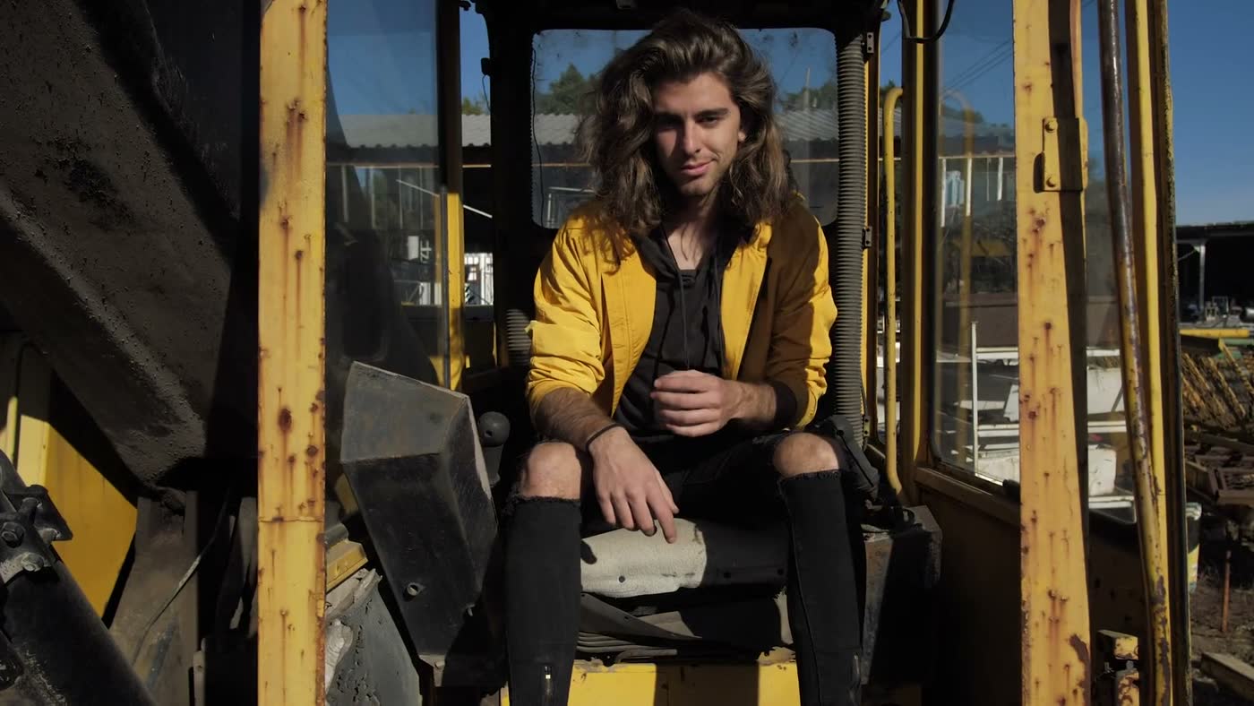 A man sitting in the cab of rusted yellow heavy equipment